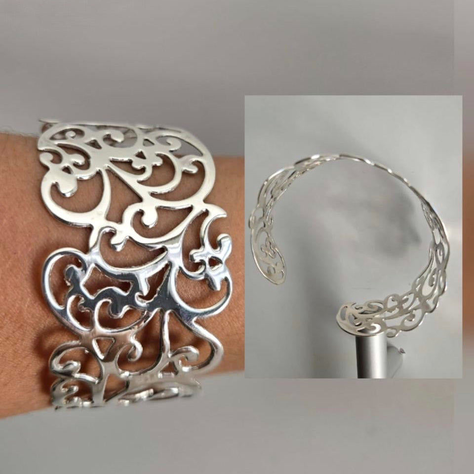 Silver bracelet with intricate design worn on a wrist, close-up view.