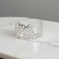 Silver bracelet with intricate design worn on a wrist, close-up view.