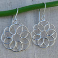 Silver circular earrings on a gray fabric background