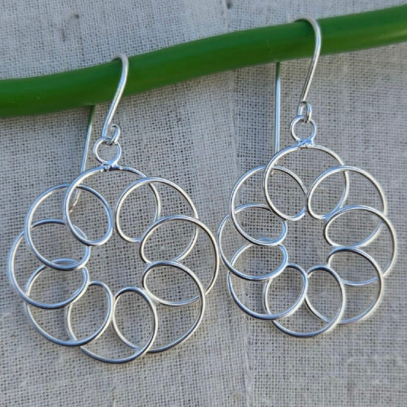Silver circular earrings on a gray fabric background