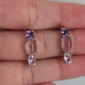 Pair of pink gemstone earrings held between fingers