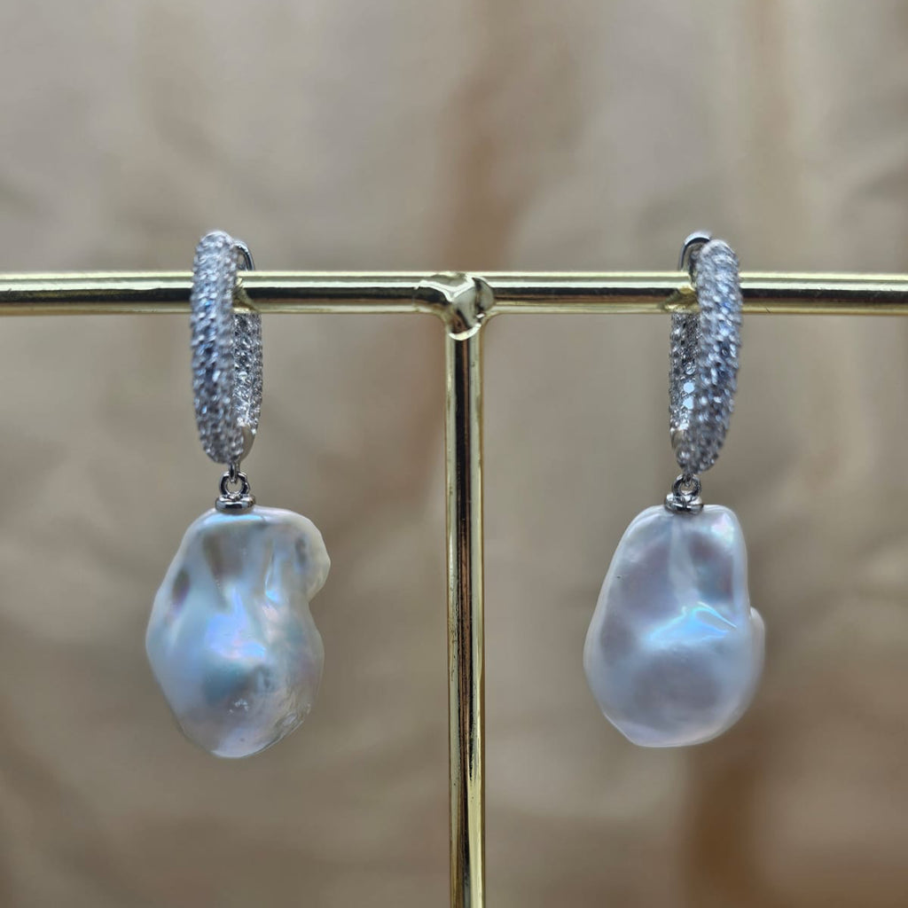 Pearl earrings on a gold stand with a blurred background