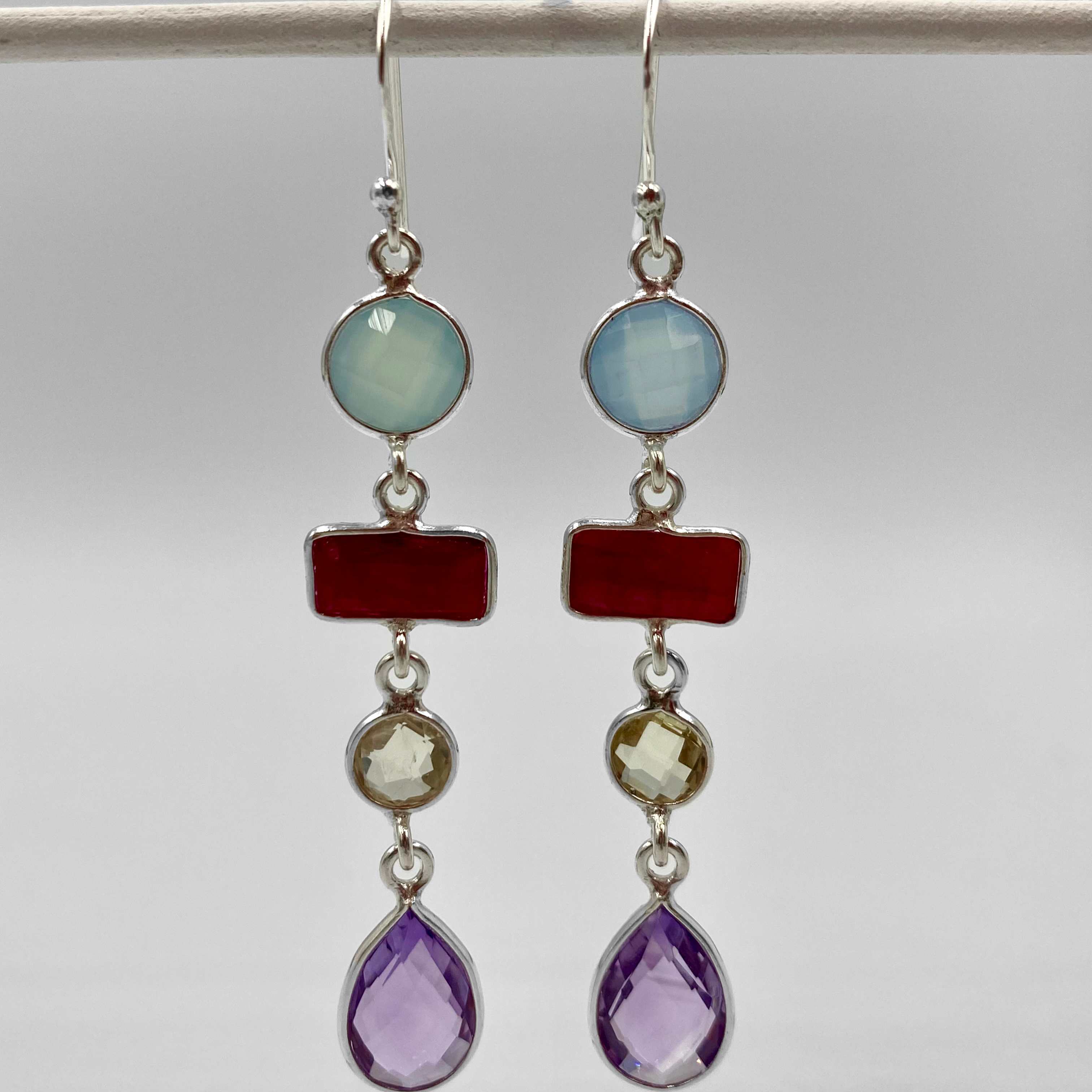 A pair of sterling silver semi-precious stone drop earrings with multiple layers, featuring colors such as blue, green, red, and purple.