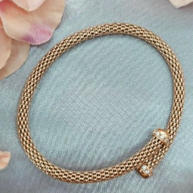 A close-up image of a rose gold-plated sterling silver bracelet with a mesh design, displayed on a pale background with soft lighting.