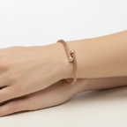A close-up image of a rose gold-plated sterling silver bracelet with a mesh design, displayed on a pale background with soft lighting.
