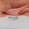 Diamond ring on a white surface with a pink fabric background