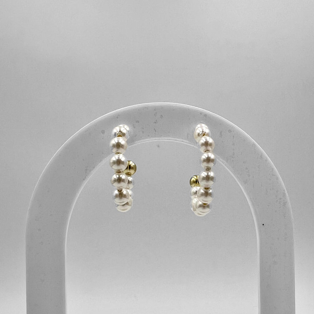 A pair of 20 mm pearl hoops earrings with gold plating on sterling silver, displayed on a stand.