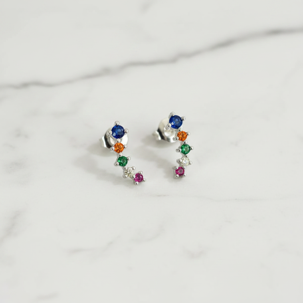 Sterling silver stud earrings with rainbow colored cubic zirconia stones displayed in a white vase with a green plant.
