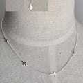 Silver necklace with small pendants on a mannequin bust.