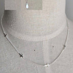 Silver necklace with small pendants on a mannequin bust.