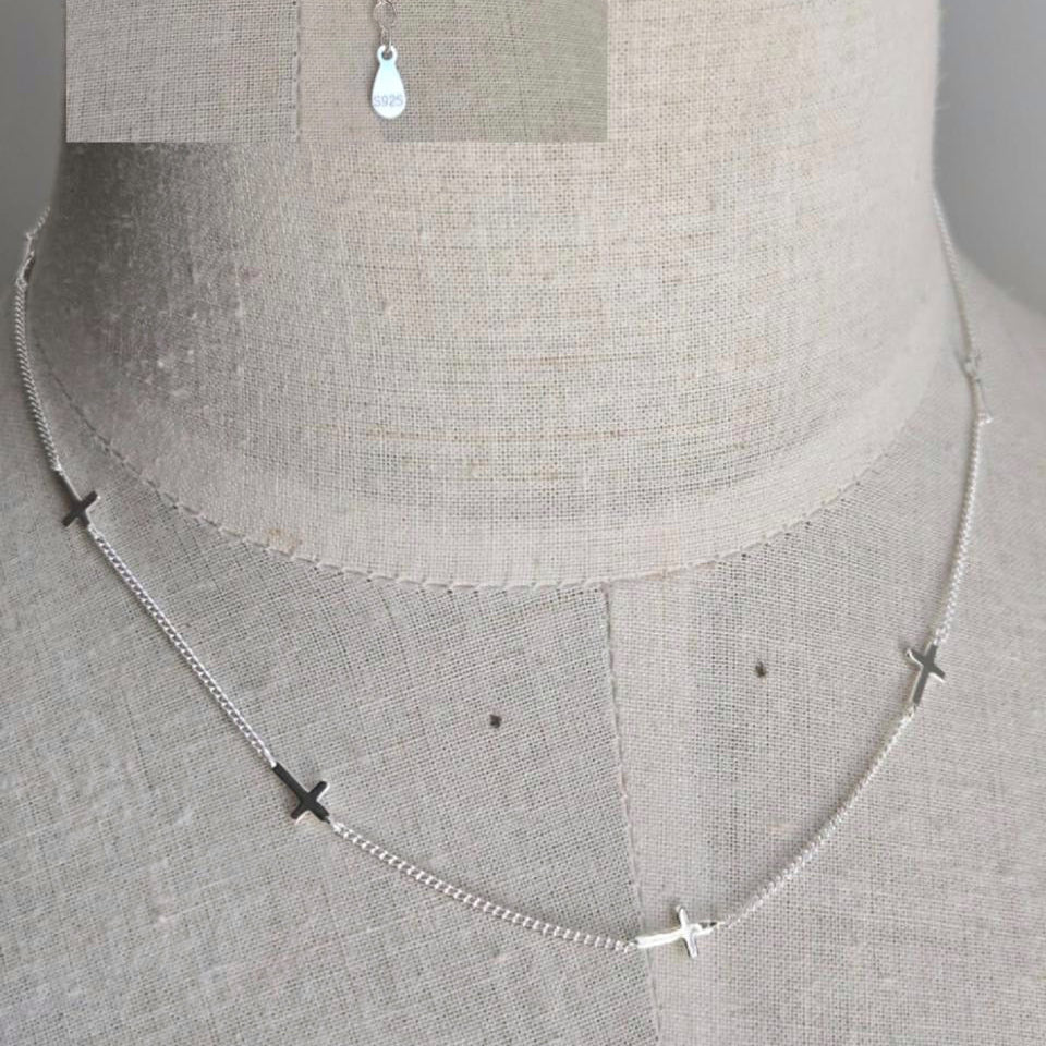 Silver necklace with small pendants on a mannequin bust.