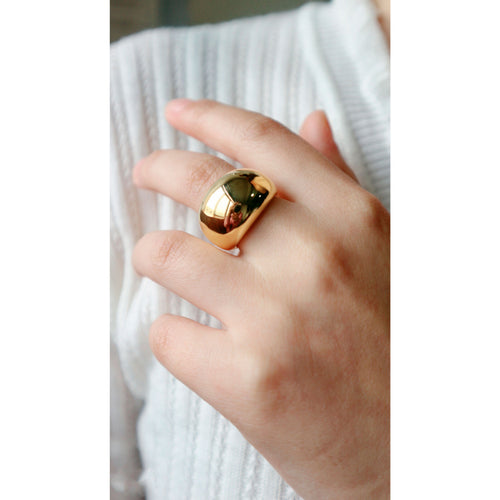 Hand wearing a gold ring with a white textured background