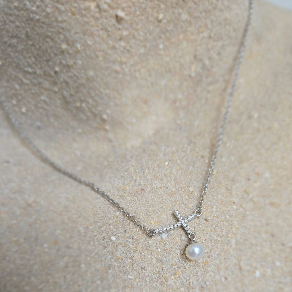 Silver necklace with a pendant on a sand background