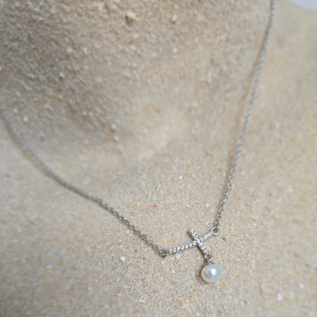 Silver necklace with a pendant on a sand background