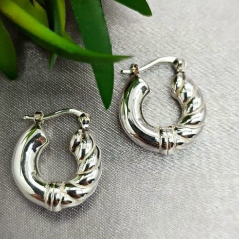 A pair of sterling silver hoop earrings with a twisted chain design, displayed on a textured background.