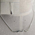 Silver necklace with a small pendant on a textured beige background