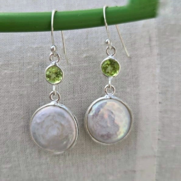 Pair of silver earrings with green gemstones on a gray background
