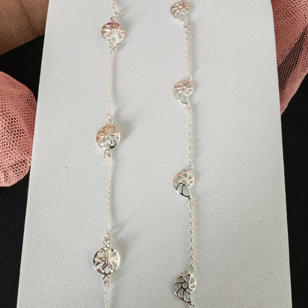 Silver necklace with heart and circular pendants on a light gray stand.