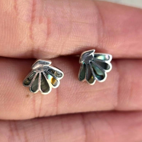 Silver leaf-shaped earrings on a person's finger