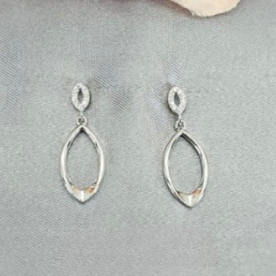 Silver teardrop earrings on a gray surface with a pink flower in the background