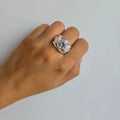 Hand wearing a decorative ring on a plain background