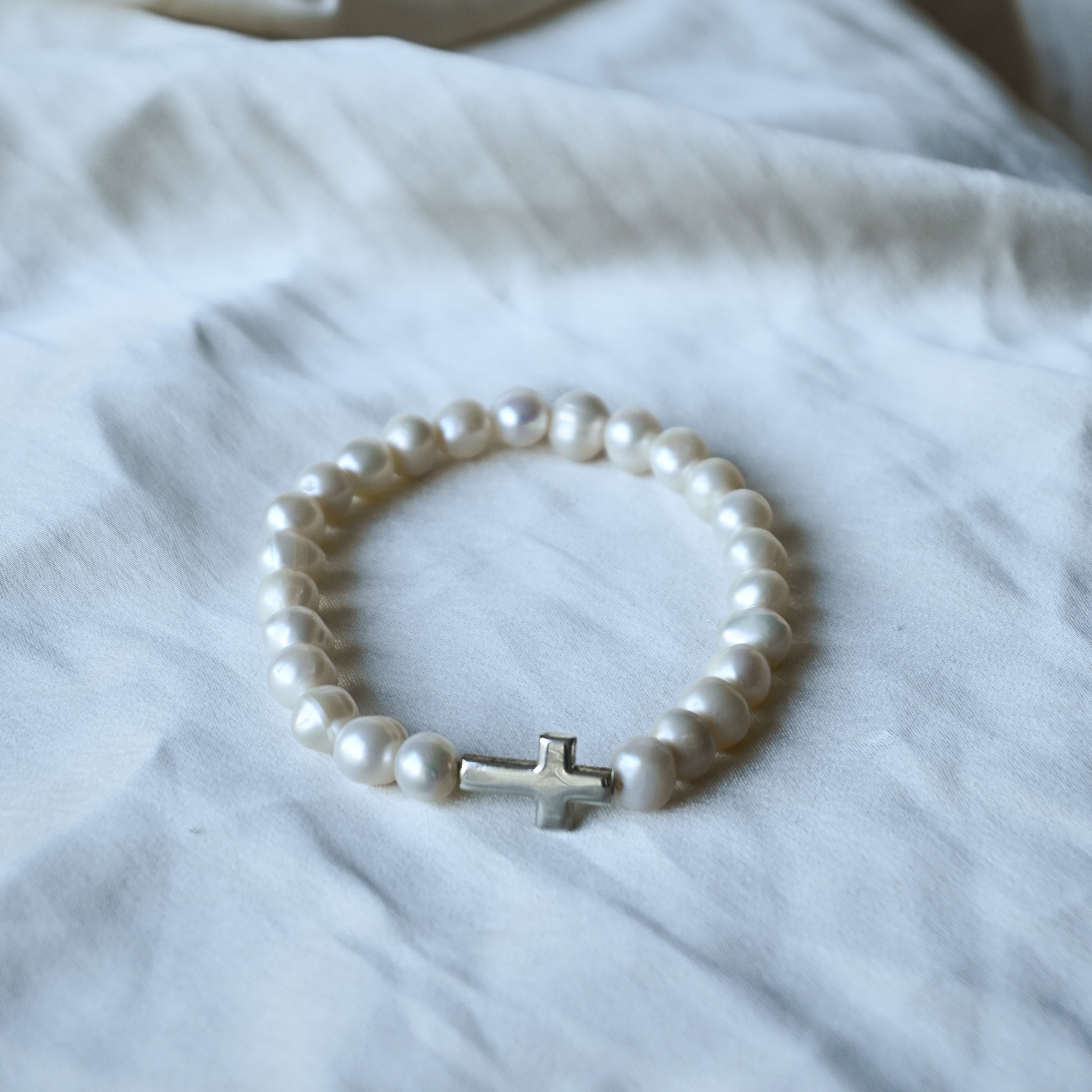 Pearl bracelet with a silver clasp on a white fabric background