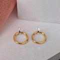 Gold hoop earrings on a light gray surface