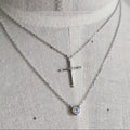 Silver necklace with a cross pendant on a mannequin.