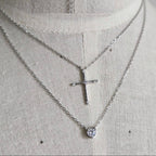 Silver necklace with a cross pendant on a mannequin.