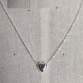 Silver heart-shaped pendant necklace on a light gray fabric background