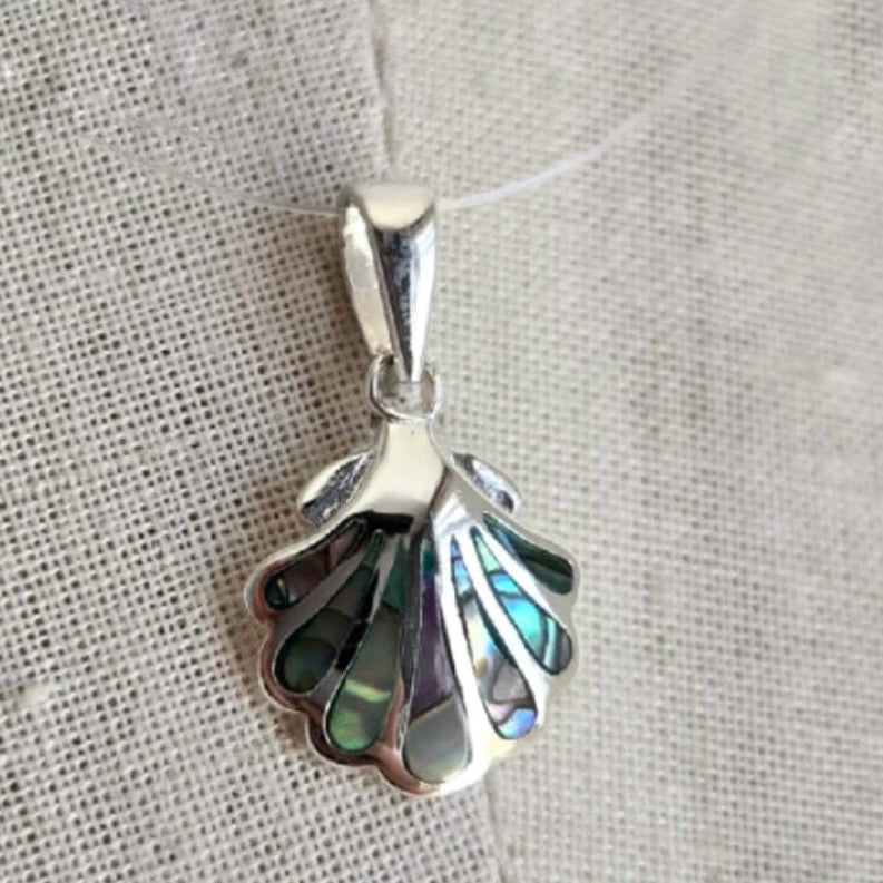Silver shell pendant with abalone interior on a textured fabric background