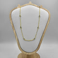 An 18c gold plated necklace with white cubic zirconia stones displayed on a wooden mannequin with a gray background.