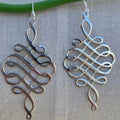 Silver Celtic knot earrings on a neutral background
