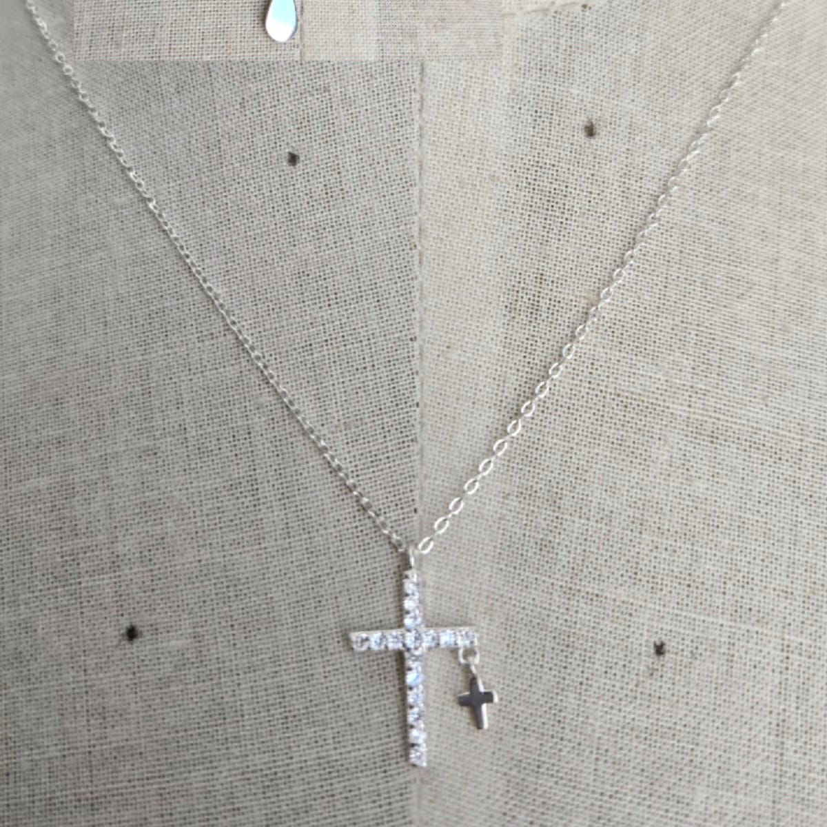 Silver cross necklace on a gray fabric background