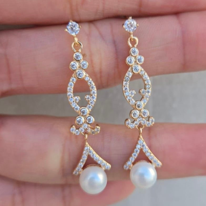 Gold earrings with pearls and crystals on a hand