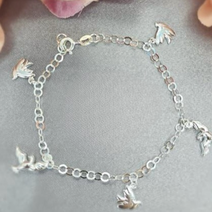 A sterling silver bracelet featuring a series of dangling doves in a chain design, displayed against a floral background.