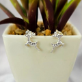 A pair of reindeer-shaped sterling silver stud earrings displayed in front of a potted plant.