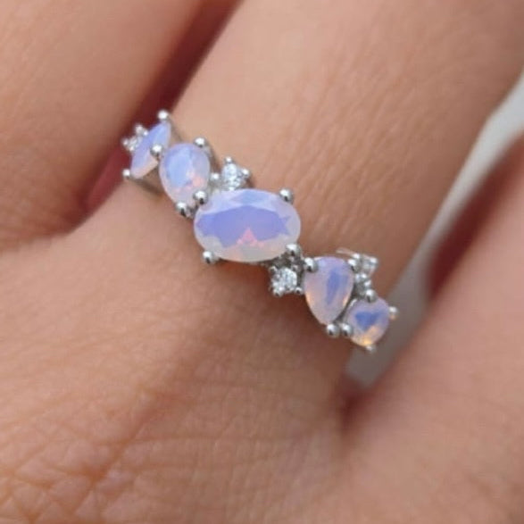 Opal ring on a finger with a plain background