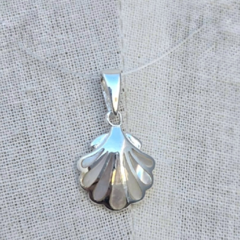 Silver shell pendant on a light fabric background