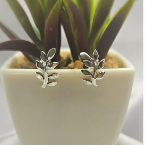 A pair of sterling silver leaf-shaped stud earrings displayed in a white pot with artificial greenery.