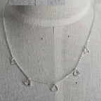Silver necklace with heart-shaped pendants on a mannequin.
