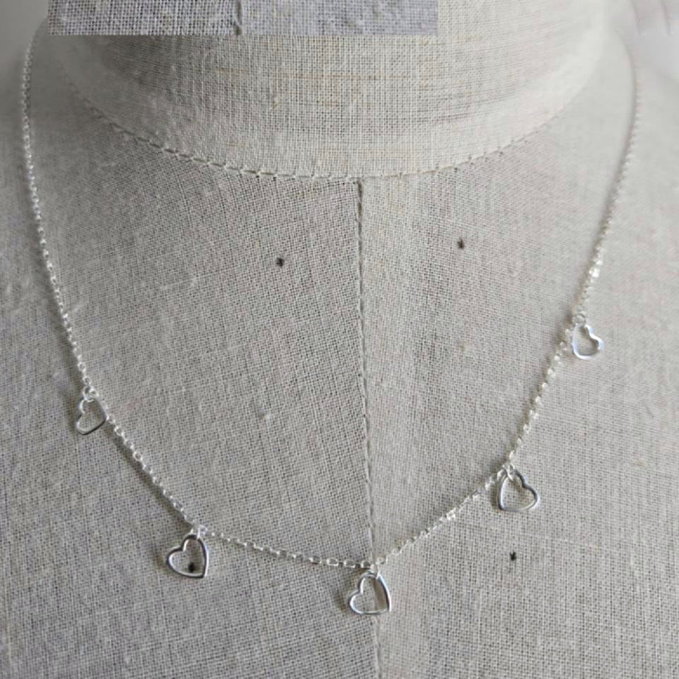 Silver necklace with heart-shaped pendants on a mannequin.