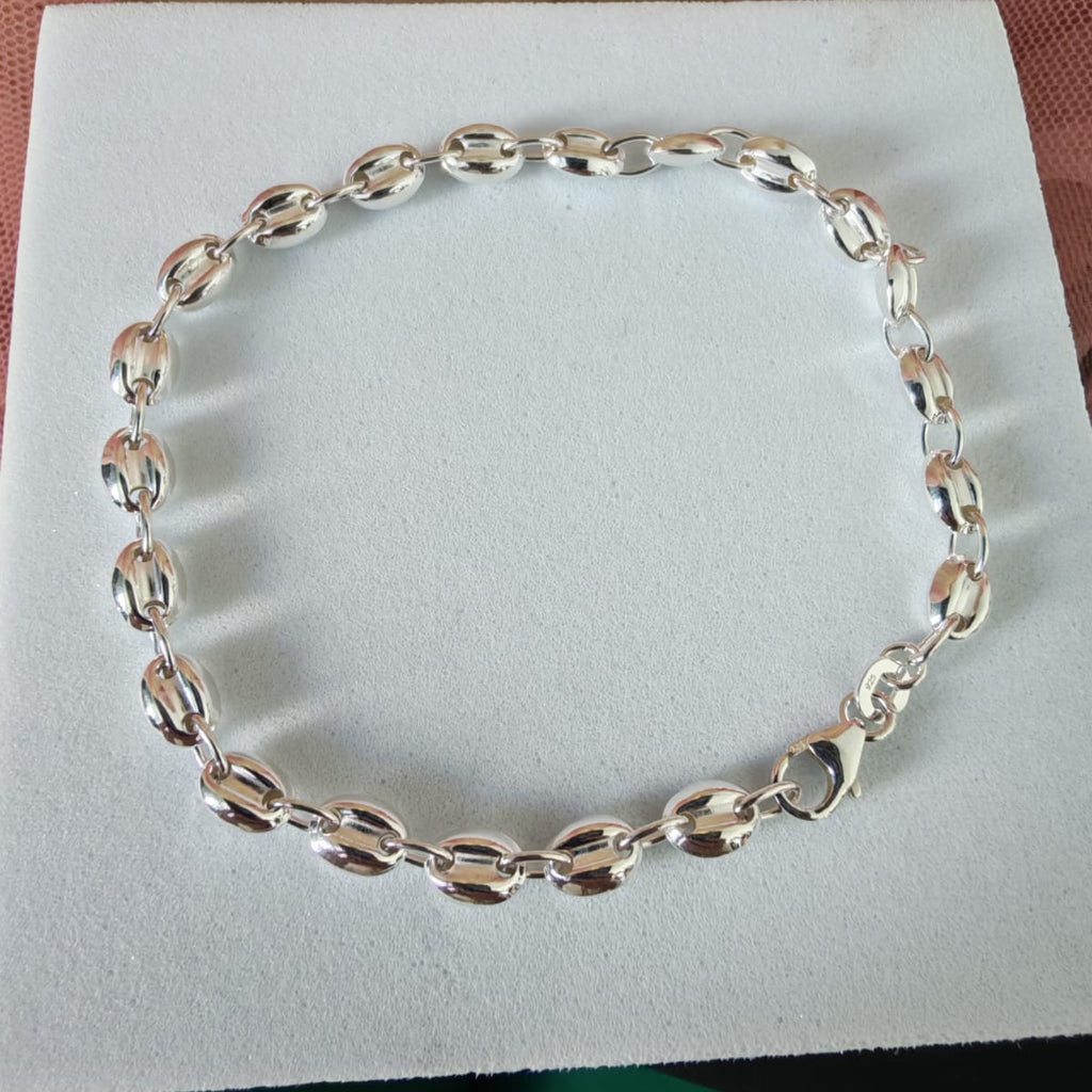 Silver chain bracelet on a white box with a wooden surface in the background