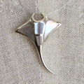 Silver shark fin pendant on a textured fabric background