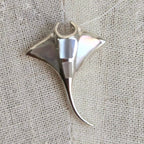 Silver shark fin pendant on a textured fabric background