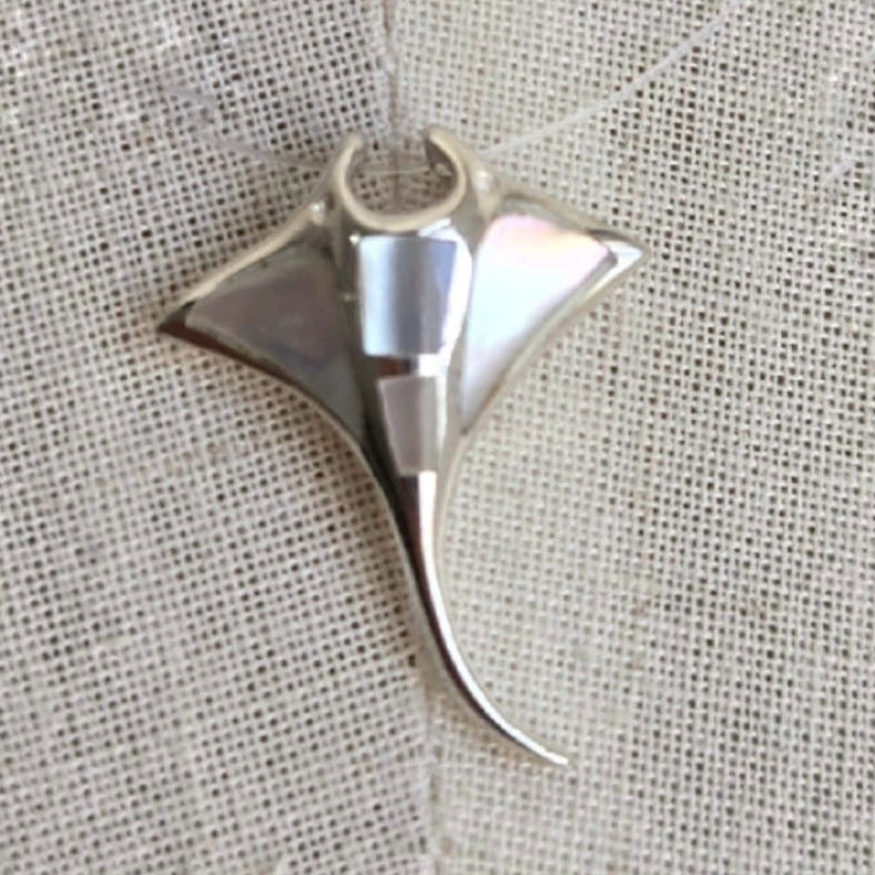 Silver shark fin pendant on a textured fabric background