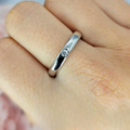 A sterling silver ring with a single cubic zirconia embedded in the band, displayed on a person's finger.