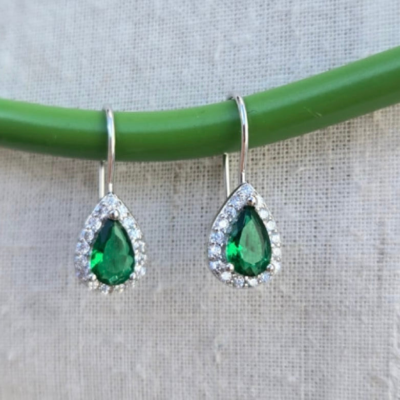 Teardrop-shaped green gemstone earrings with silver accents on a neutral background