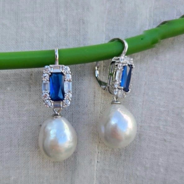 Pearl earrings with blue gemstones on a light gray background