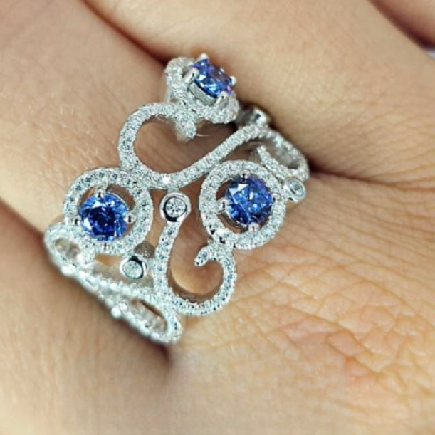 A sterling silver filigree statement ring with blue cubic zirconia accents.